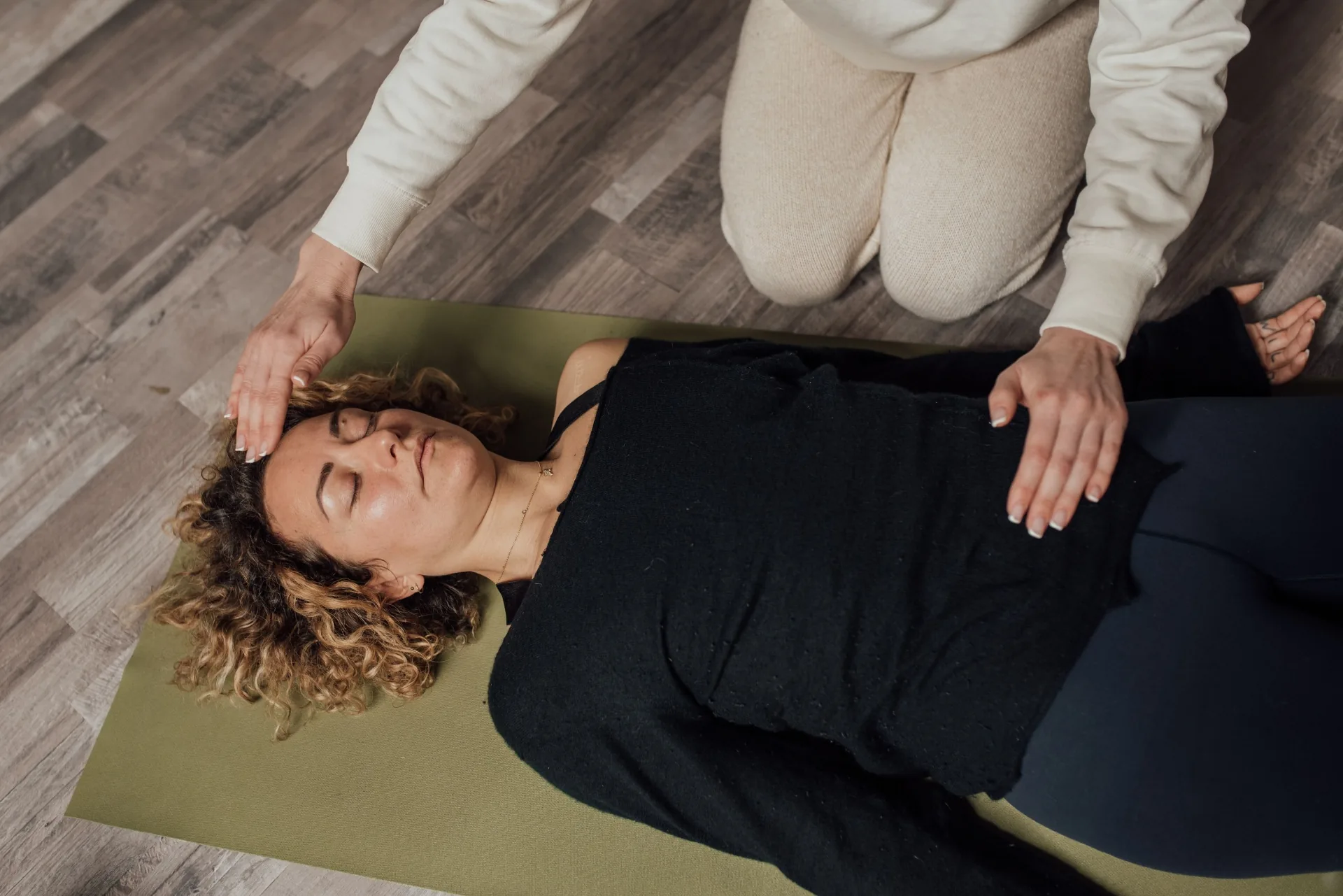 Practitioner channeling Reiki energy over a person resting on a mat